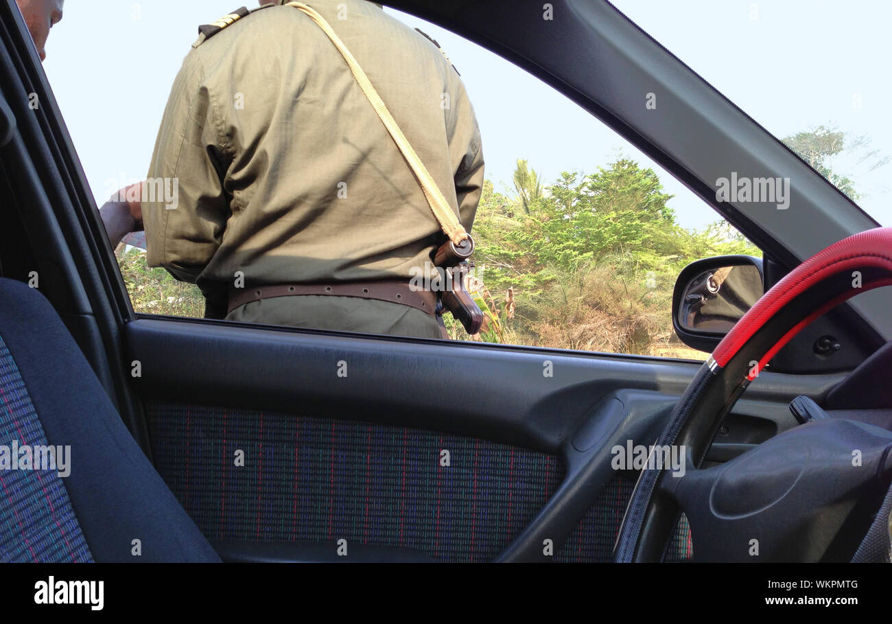 African checkpoint with armed police officer looking at driver's paperwork Stock Photo