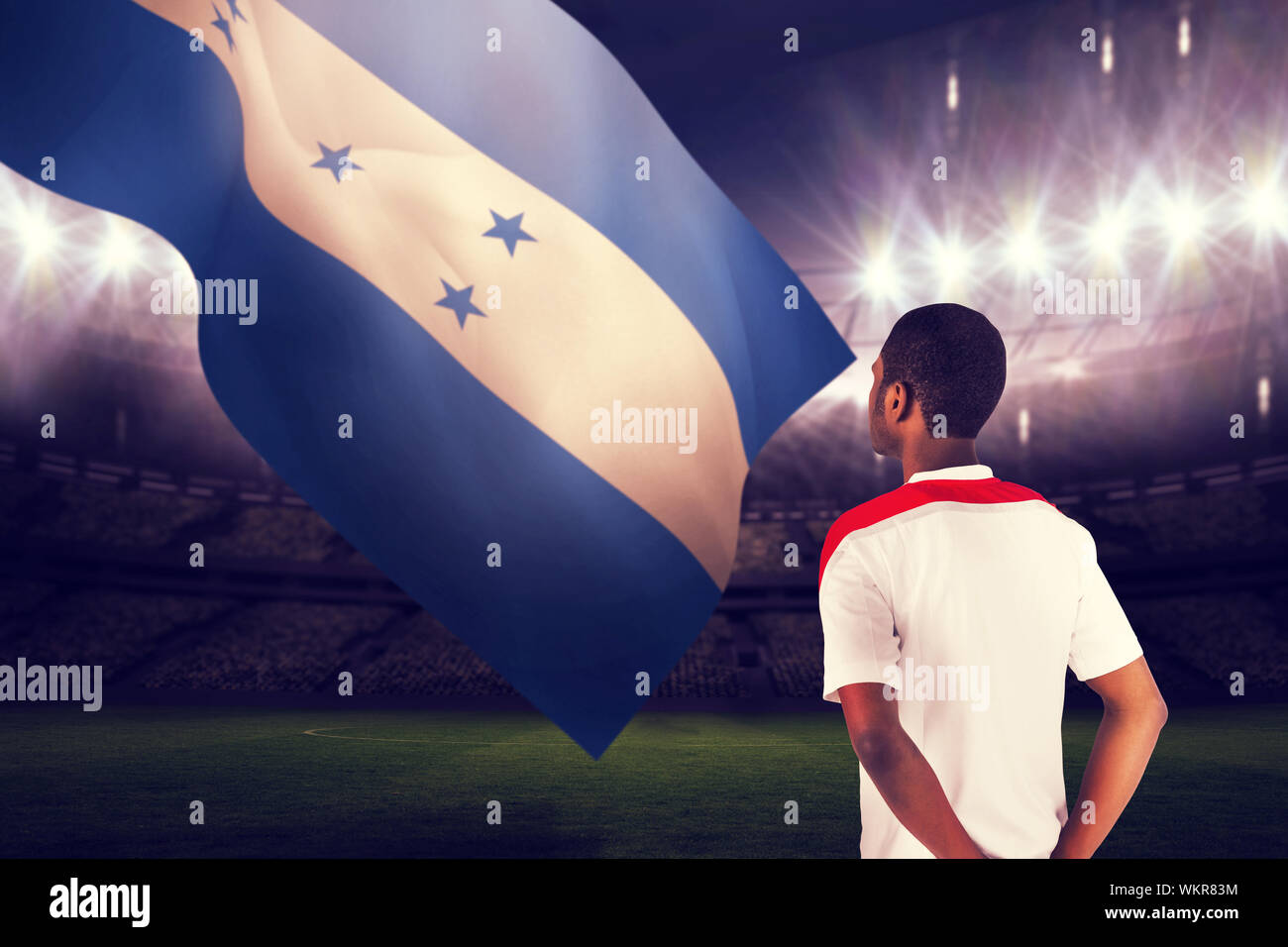 Football fan in white standing against large football stadium under night sky Stock Photo