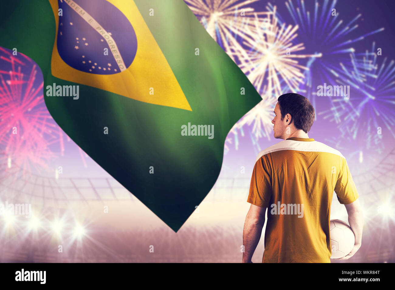 Football player in yellow holding ball against fireworks exploding over