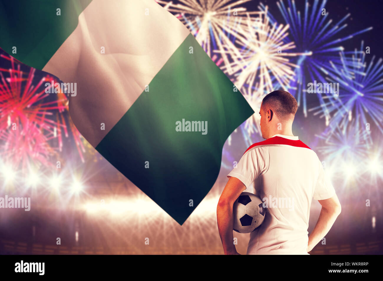 Football player holding the ball against fireworks exploding over football stadium Stock Photo