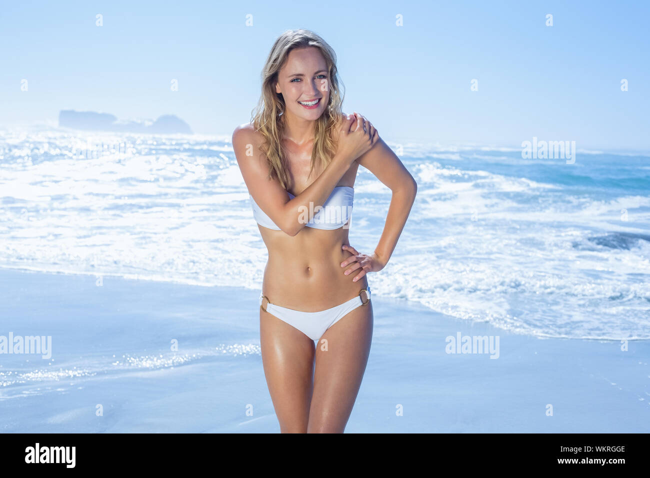 Gorgeous blonde in white bikini standing by the sea on a sunny day Stock Photo