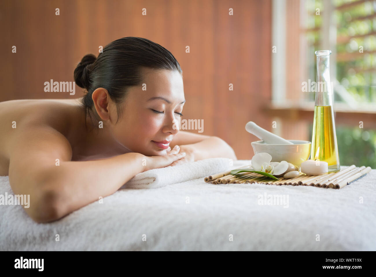 Brunette lying on massage table with tray of beauty treatments at the health spa Stock Photo