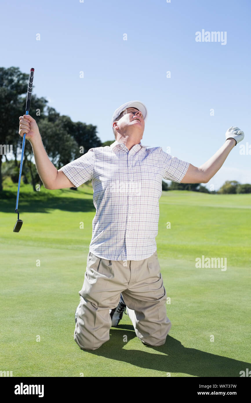 Kneeling golfer cheering on putting green on a sunny day at the golf