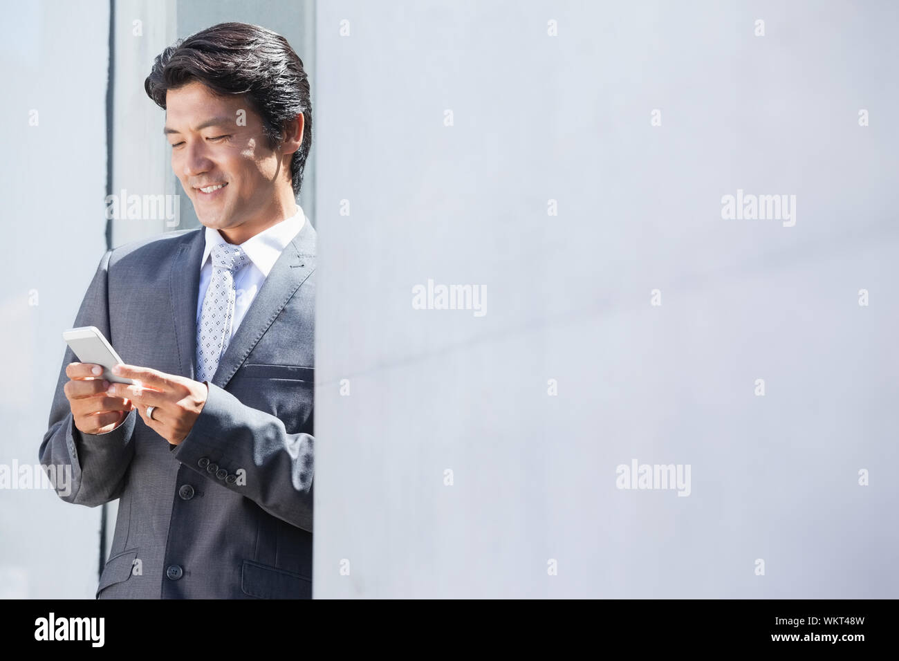 Asian businessman sending text message outside a house Stock Photo