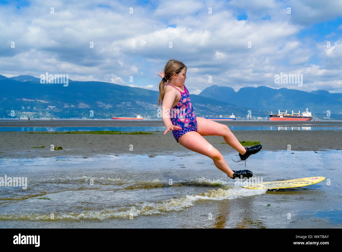Young girl skimboarding, Spanish Banks, English Bay, Vancouver, British Columbia, Canada Stock Photo
