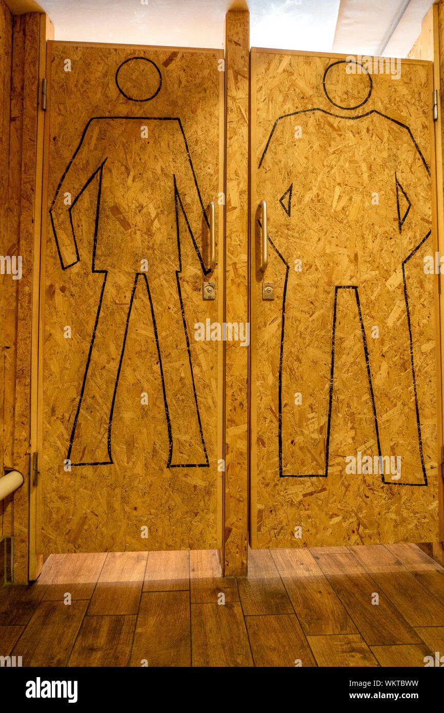 Drawn outline of a man on wood chip doors in a gents toilet Stock Photo