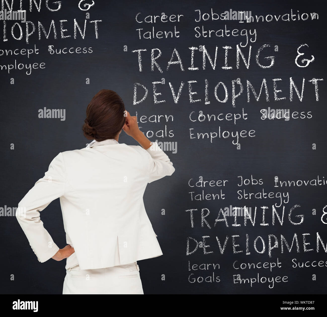 Thinking businesswoman against blackboard with business buzzwords Stock Photo