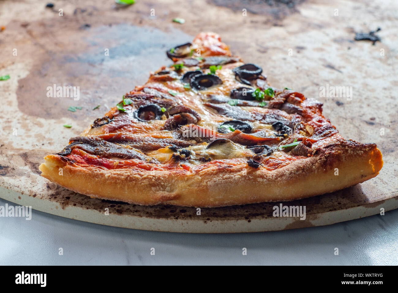 New York style slice of pizza with anchovies and black olives Stock