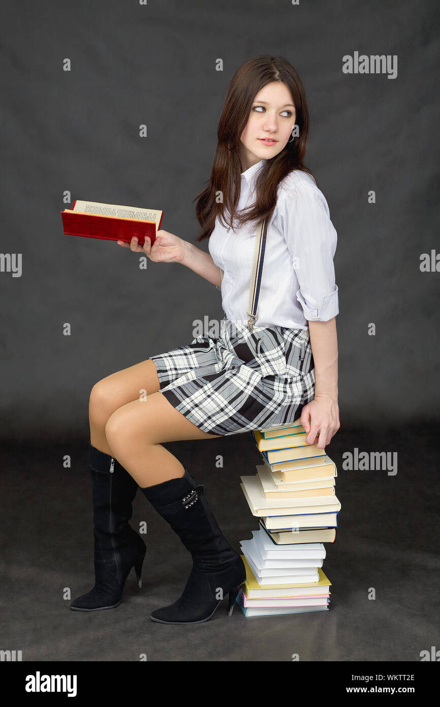 Schoolgirl with the big pile of books on a black background Stock Photo ...