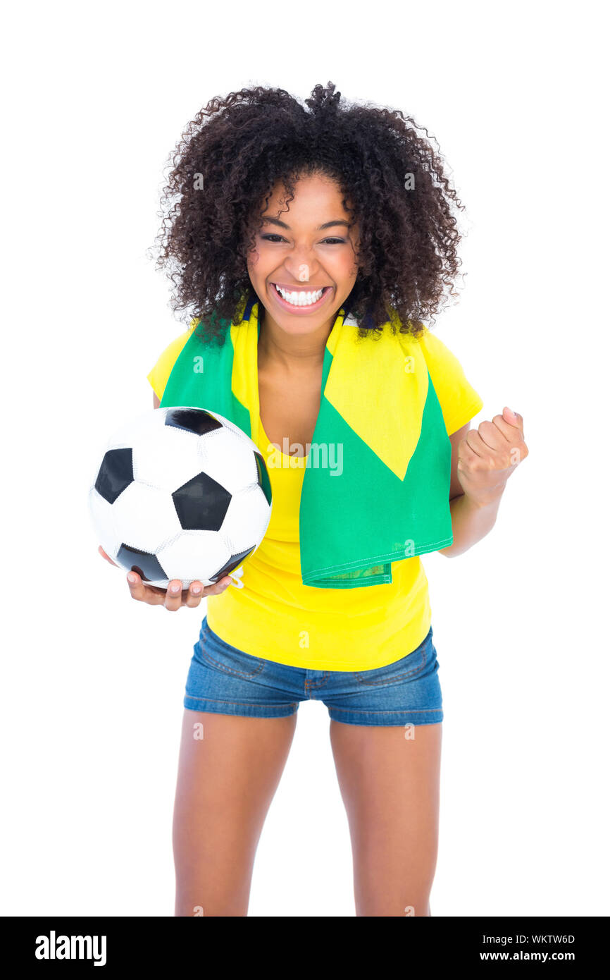 Pretty football fan holding brazilian flag cheering at camera  on white background Stock Photo