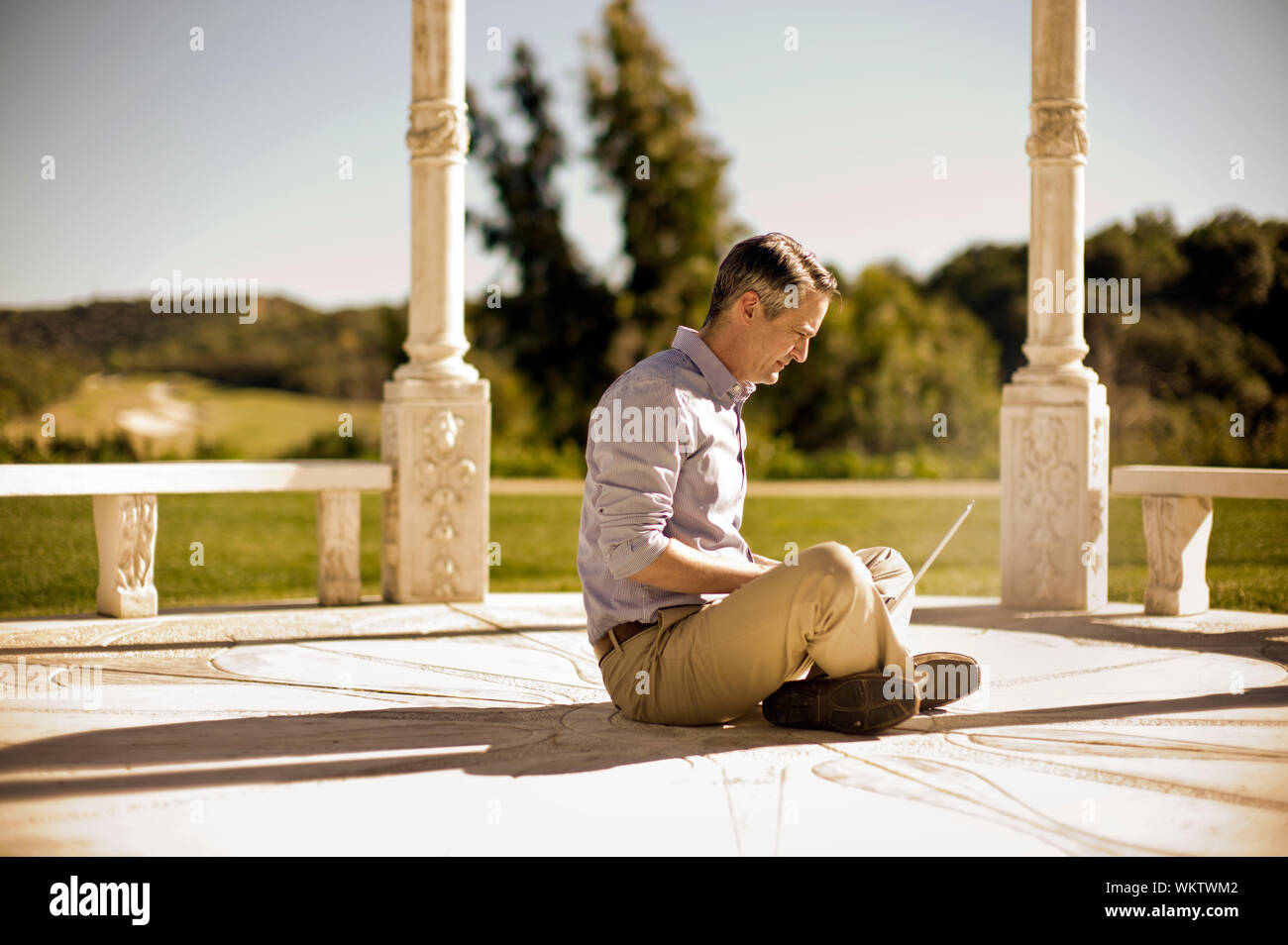 Man sitting outside in a rotunda,  using his laptop. Stock Photo