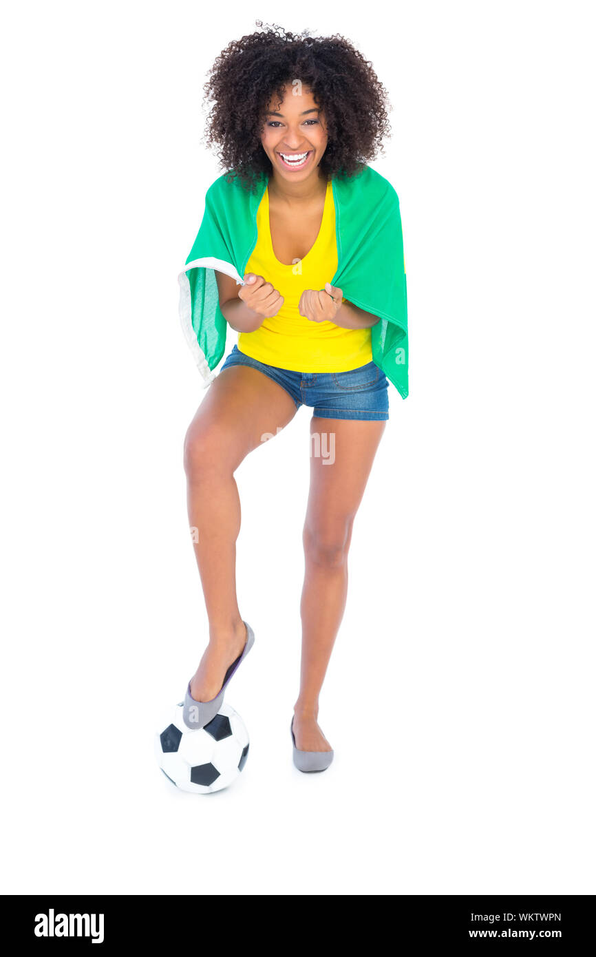 Pretty football fan holding brazilian flag cheering at camera on white background Stock Photo