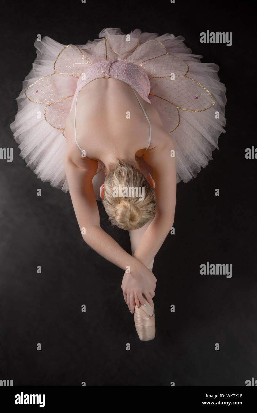 Graceful ballerina bending forward in pink tutu in the ballet studio Stock Photo