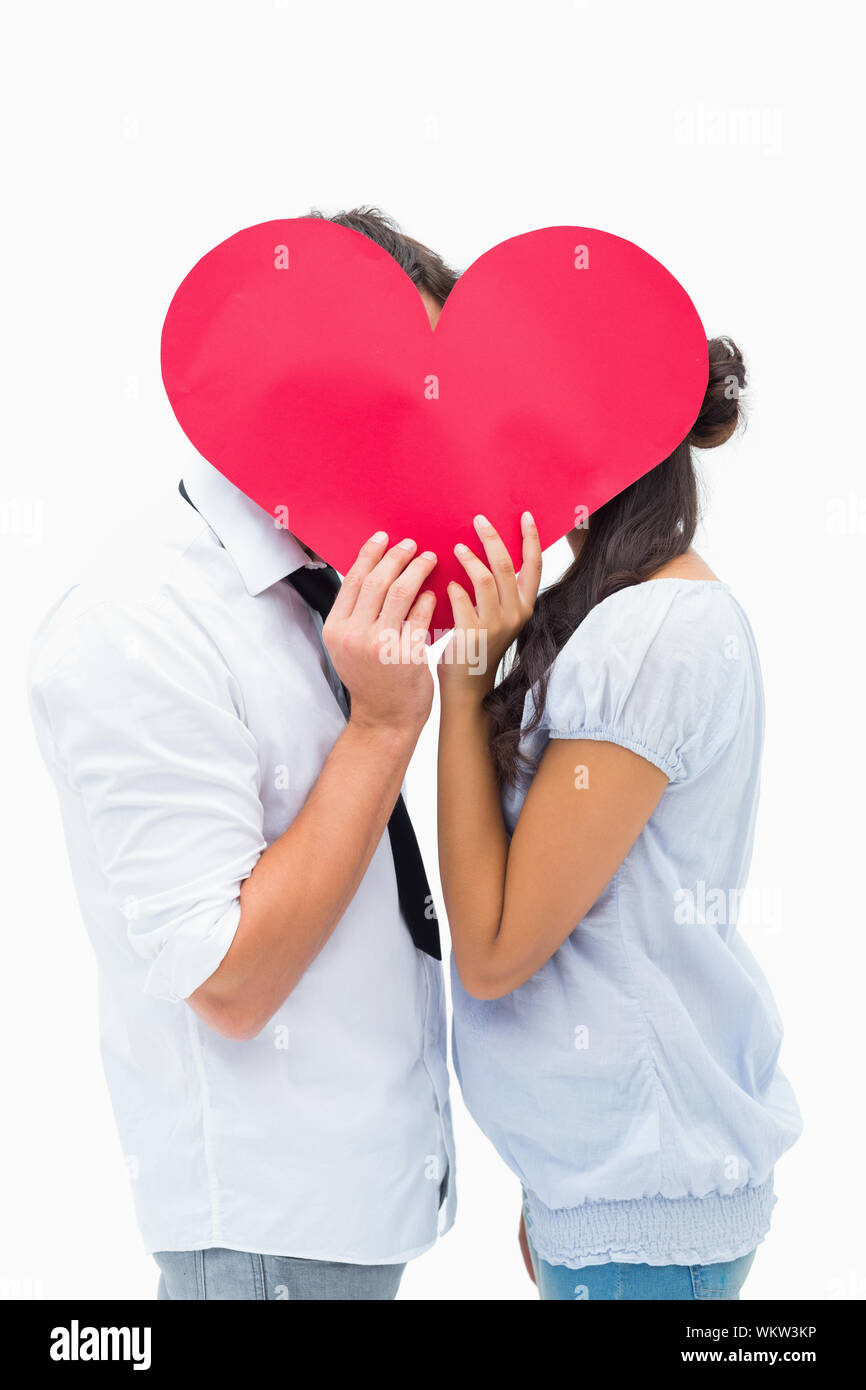 Couple covering their kiss with a heart on white background Stock Photo ...