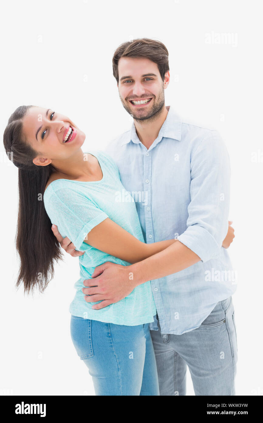 Attractive young couple hugging and smiling at camera on white ...