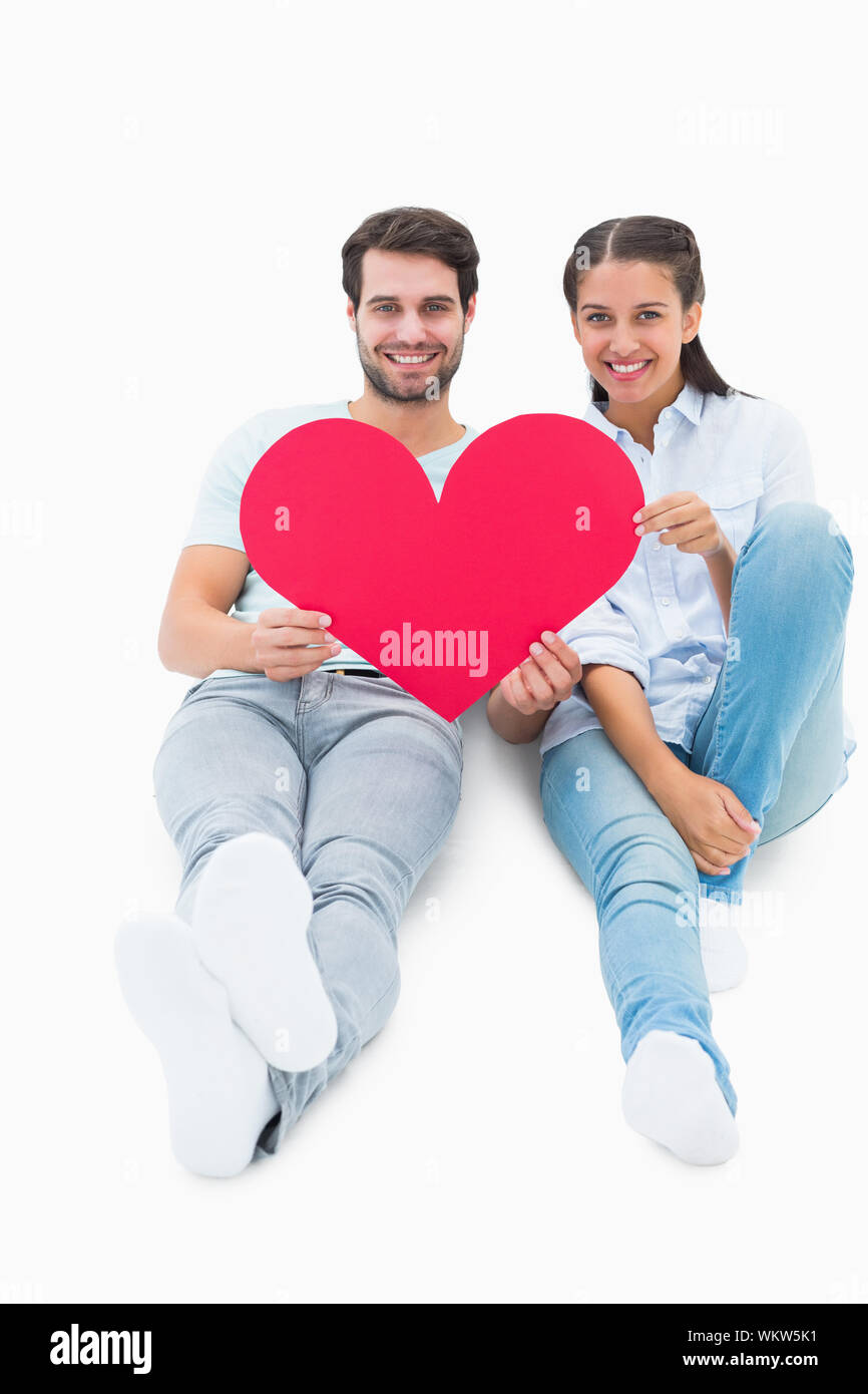 Cute couple sitting holding red heart on white background Stock Photo ...