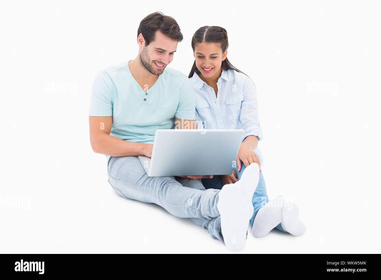 Cute couple sitting using the laptop on white background Stock Photo ...