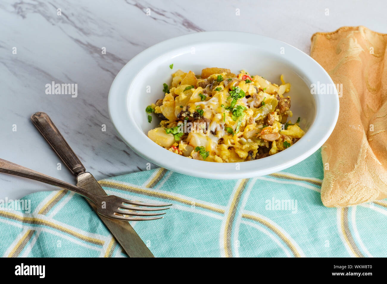 Breakfast egg scramble bowl with sausage potatoes mushrooms and cheddar