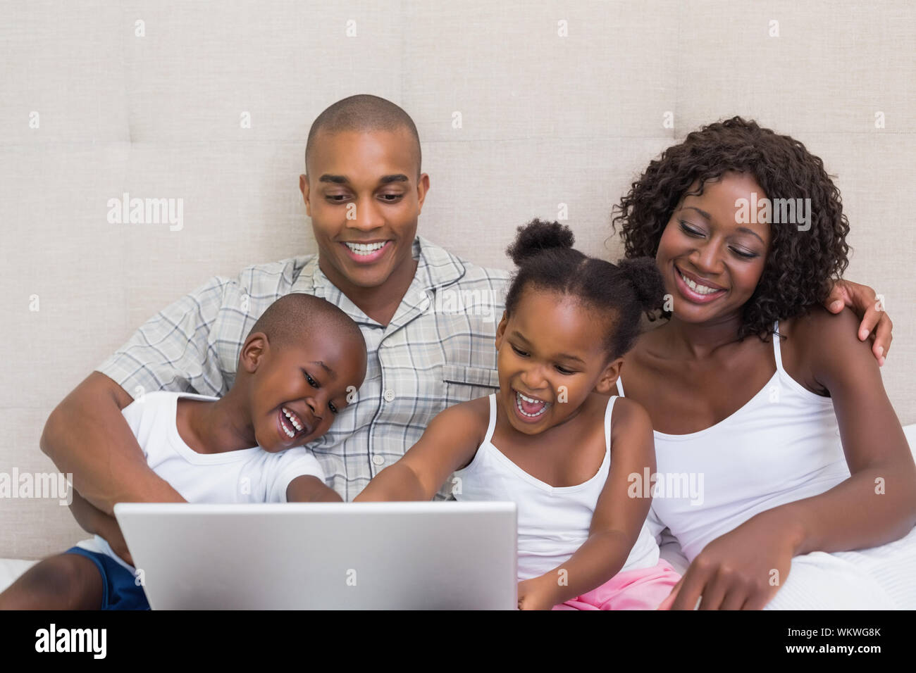 Happy family using laptop together on bed at home in the bedroom Stock ...