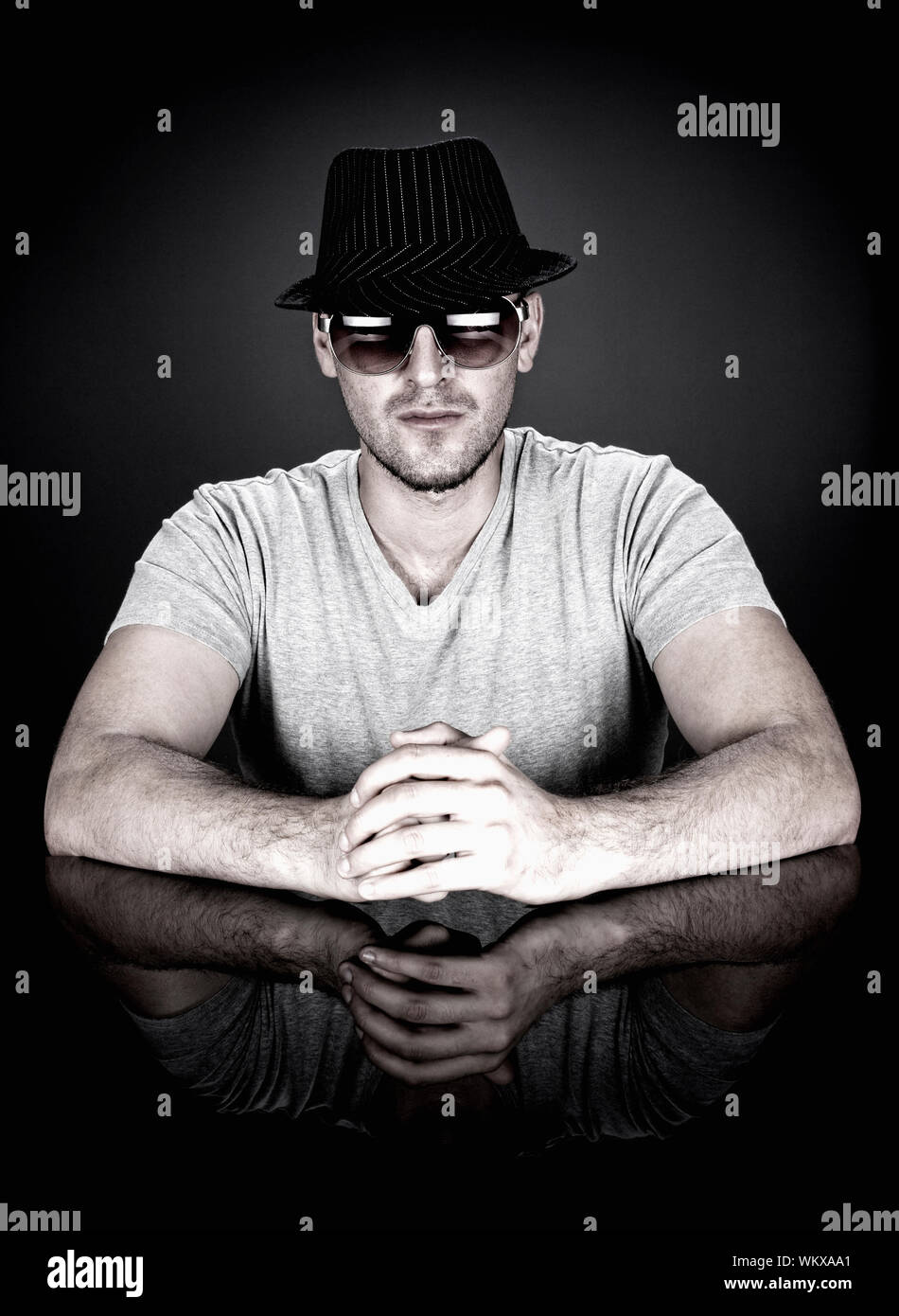 man in hat and sunglasses sitting behind desk looking at camera Stock ...