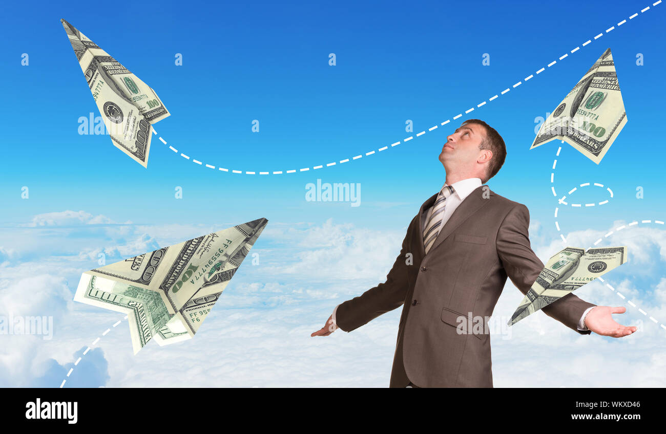 Businessman in suit spread his arms and looking up. Paper airplanes made of hundred dollar bills Stock Photo