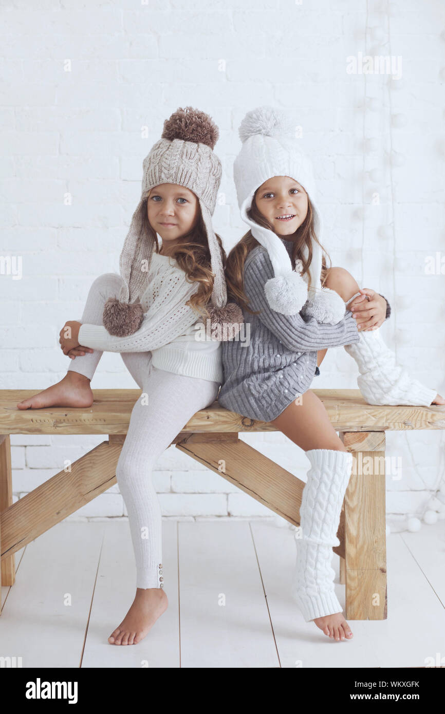 Cute little girls of 5 years old wearing knitted trendy winter clothes  posing over white brick wall Stock Photo - Alamy