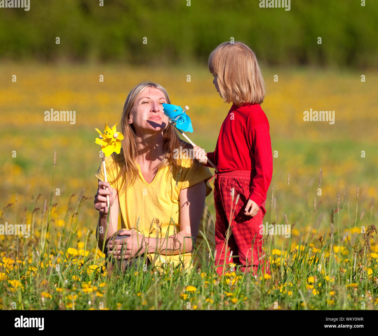 mother and son playing with pinwheels in a dandelion field Stock Photo ...