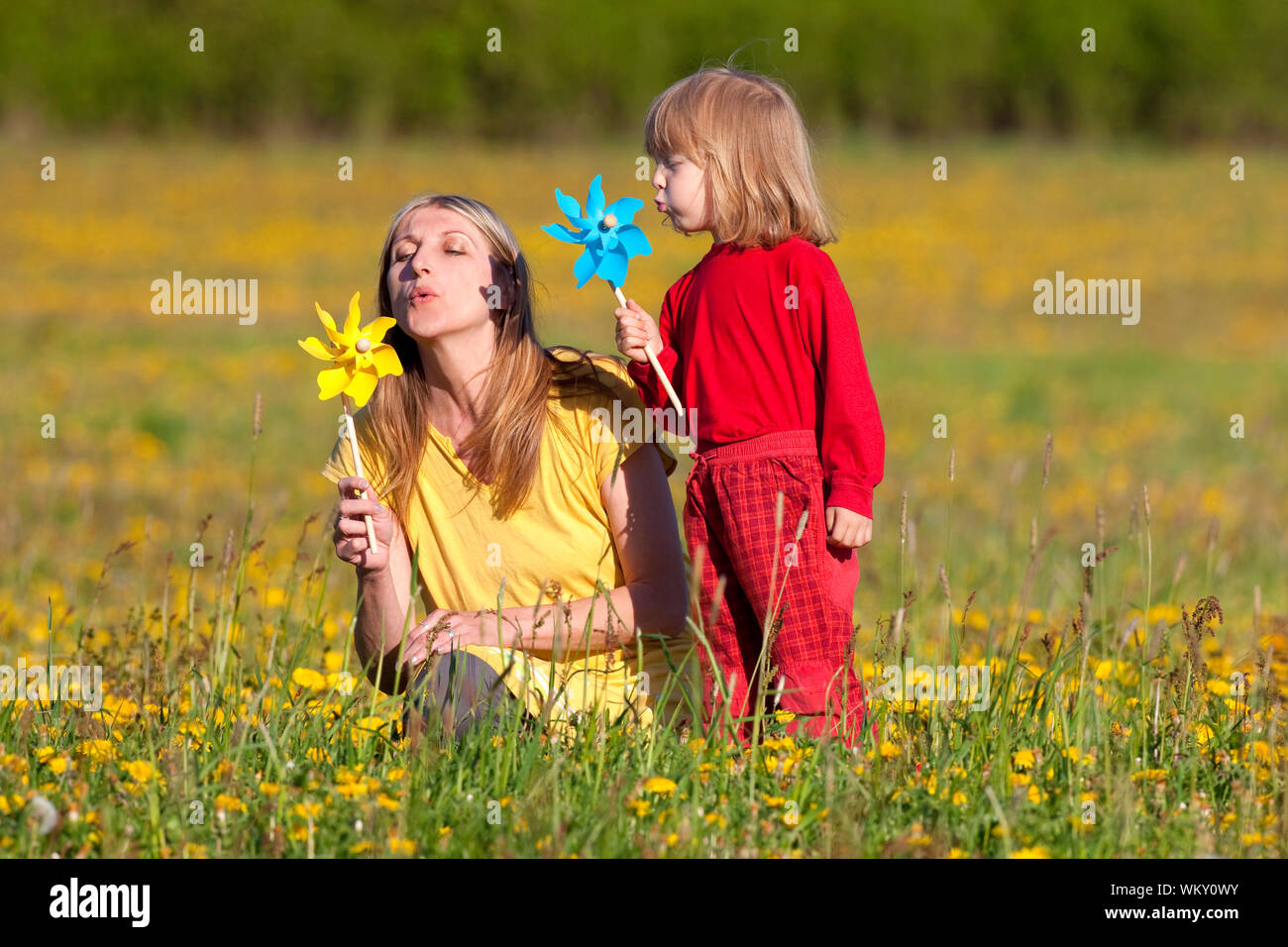 mother and son playing with pinwheels in a dandelion field Stock Photo ...