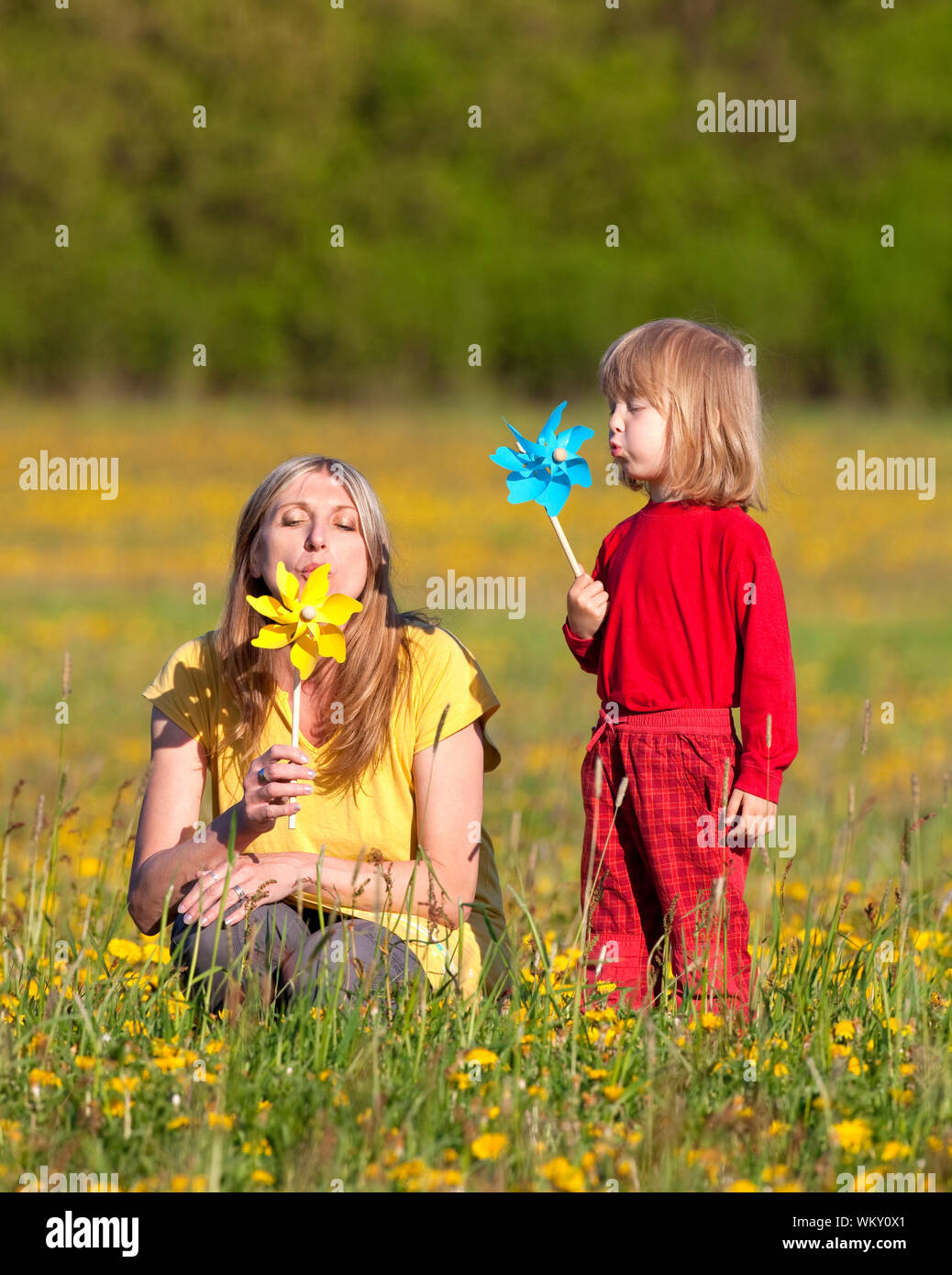mother and son playing with pinwheels in a dandelion field Stock Photo ...