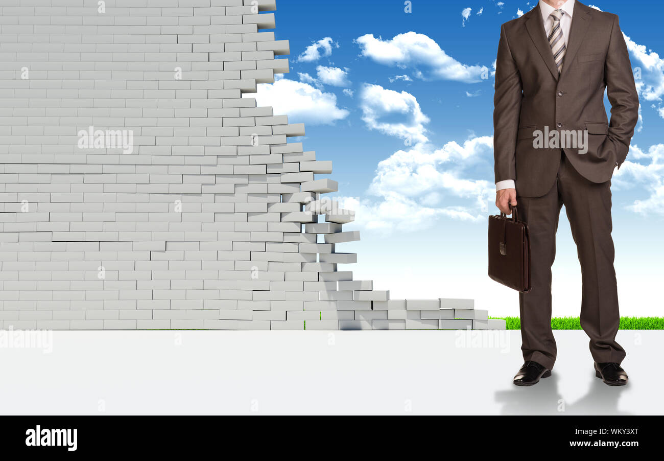 Businessman in suitcase with briefcase. Ruined brick wall and nature