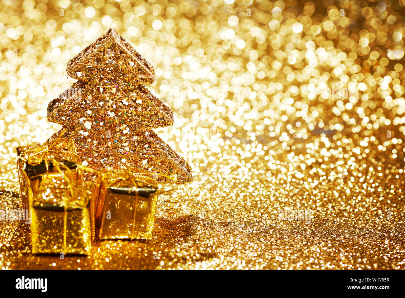 Beautiful golden decorative christmas tree and gifts on golden glitter ...