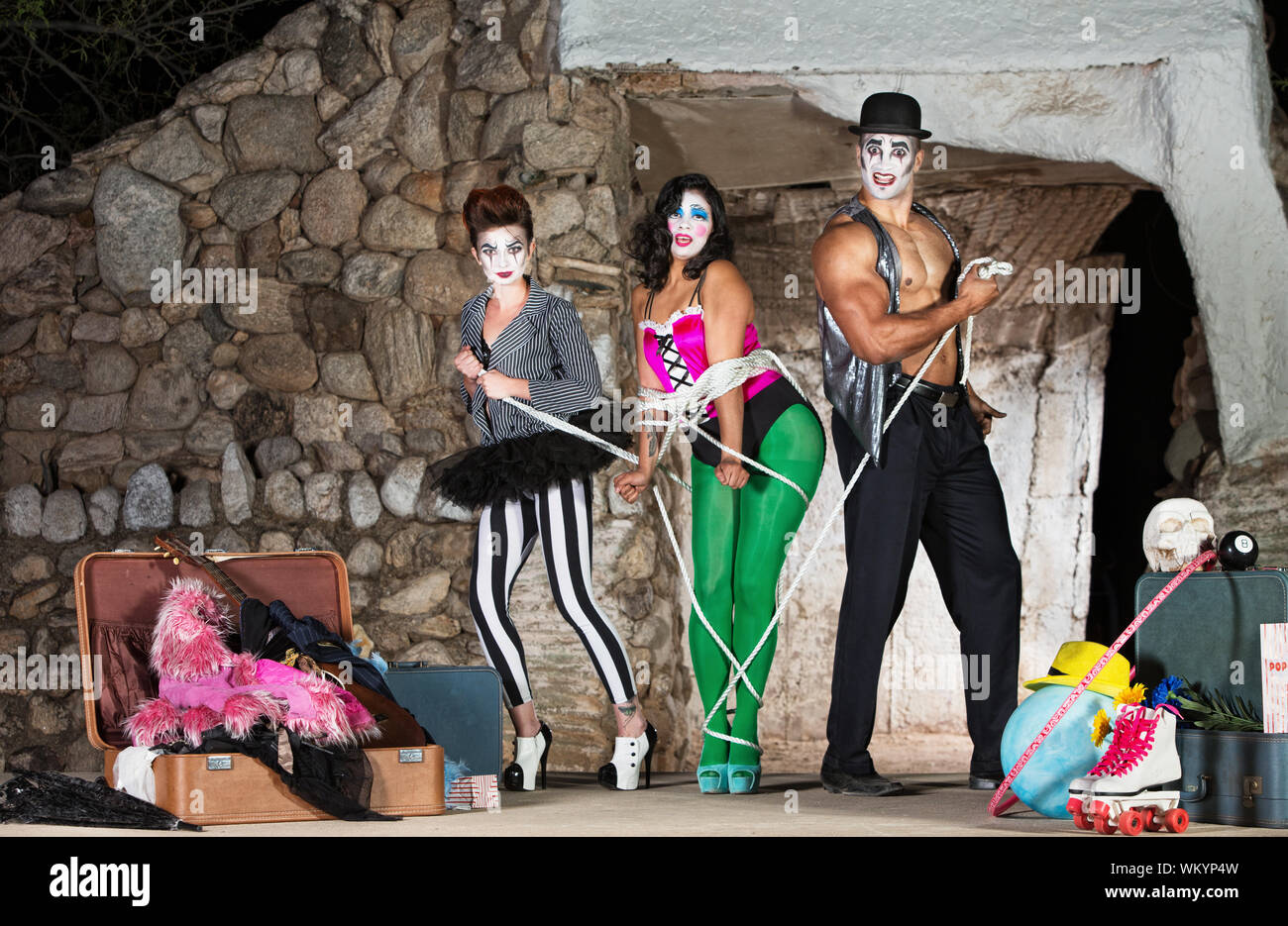 Funny cirque clowns tying up woman with rope Stock Photo