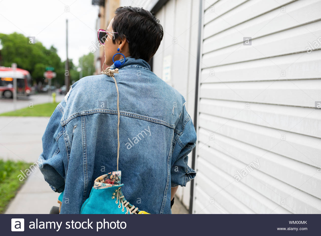 Young woman walking on sidewalk, carrying roller skates Stock Photo Alamy