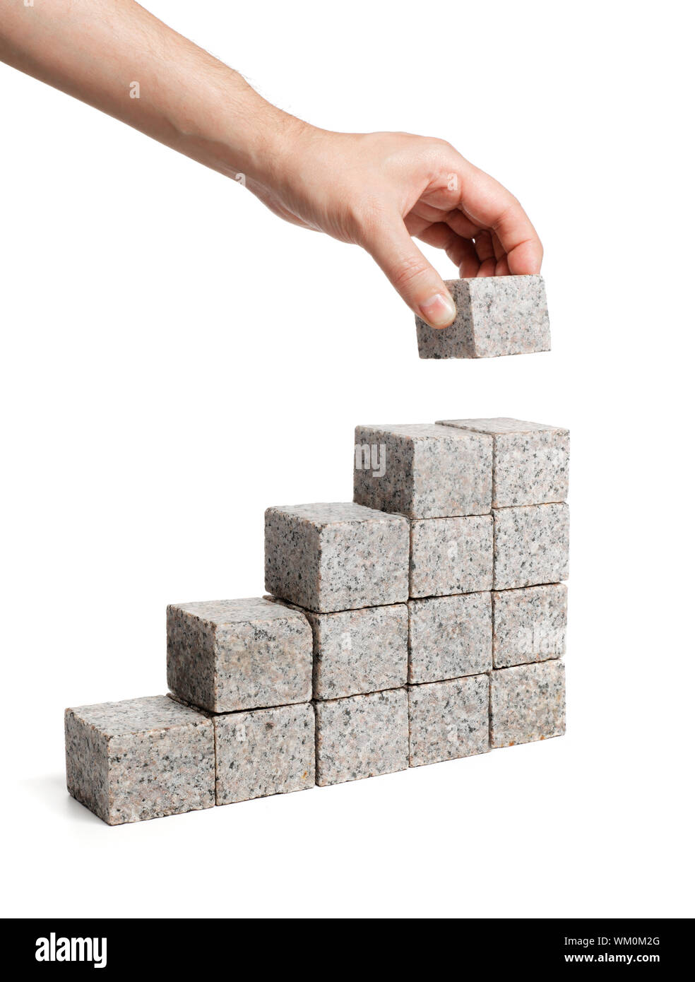 Man stacking blocks made of granite rock. Stock Photo