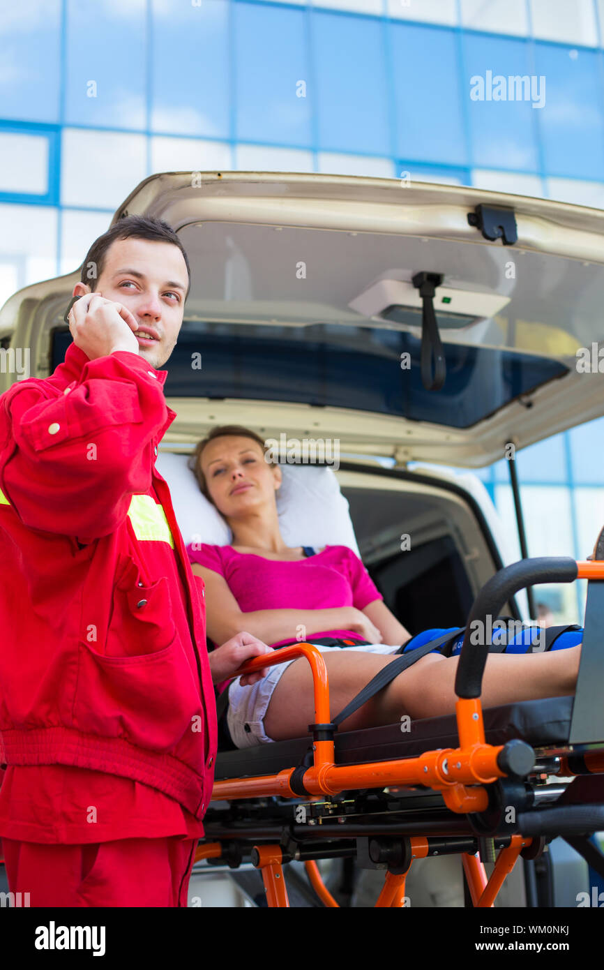 Paramedic taking care of a female patient - calling a hospital Stock Photo