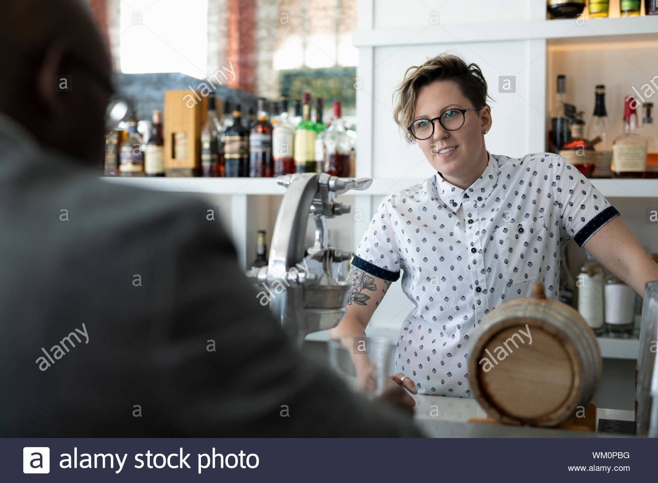 Bar owner talking to customer at bar Stock Photo Alamy