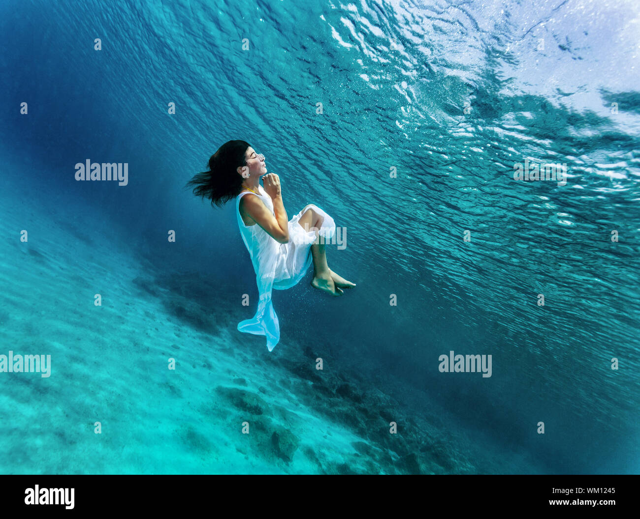 Happy girl dancing underwater, wearing stylish dress, luxury sea