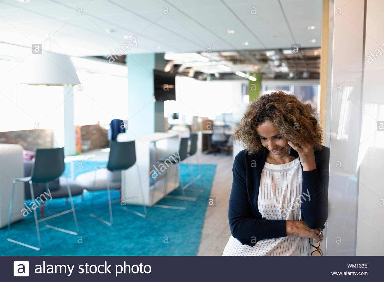 Mature woman on cell phone in open plan office Stock Photo