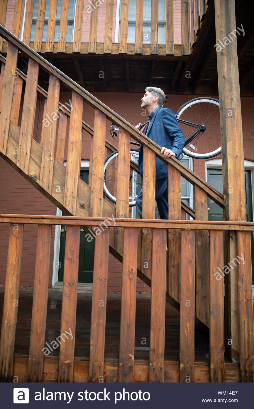 Man carrying bicycle up apartment stairs Stock Photo Alamy