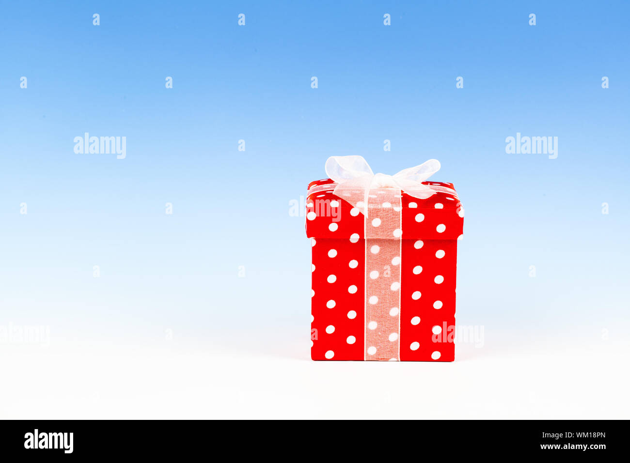 red gift box, polka dots with bow on blue background Stock Photo