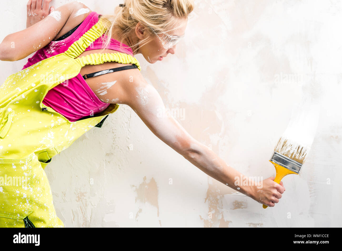 Female Worker In Coverall Painting Wall Stock Photo