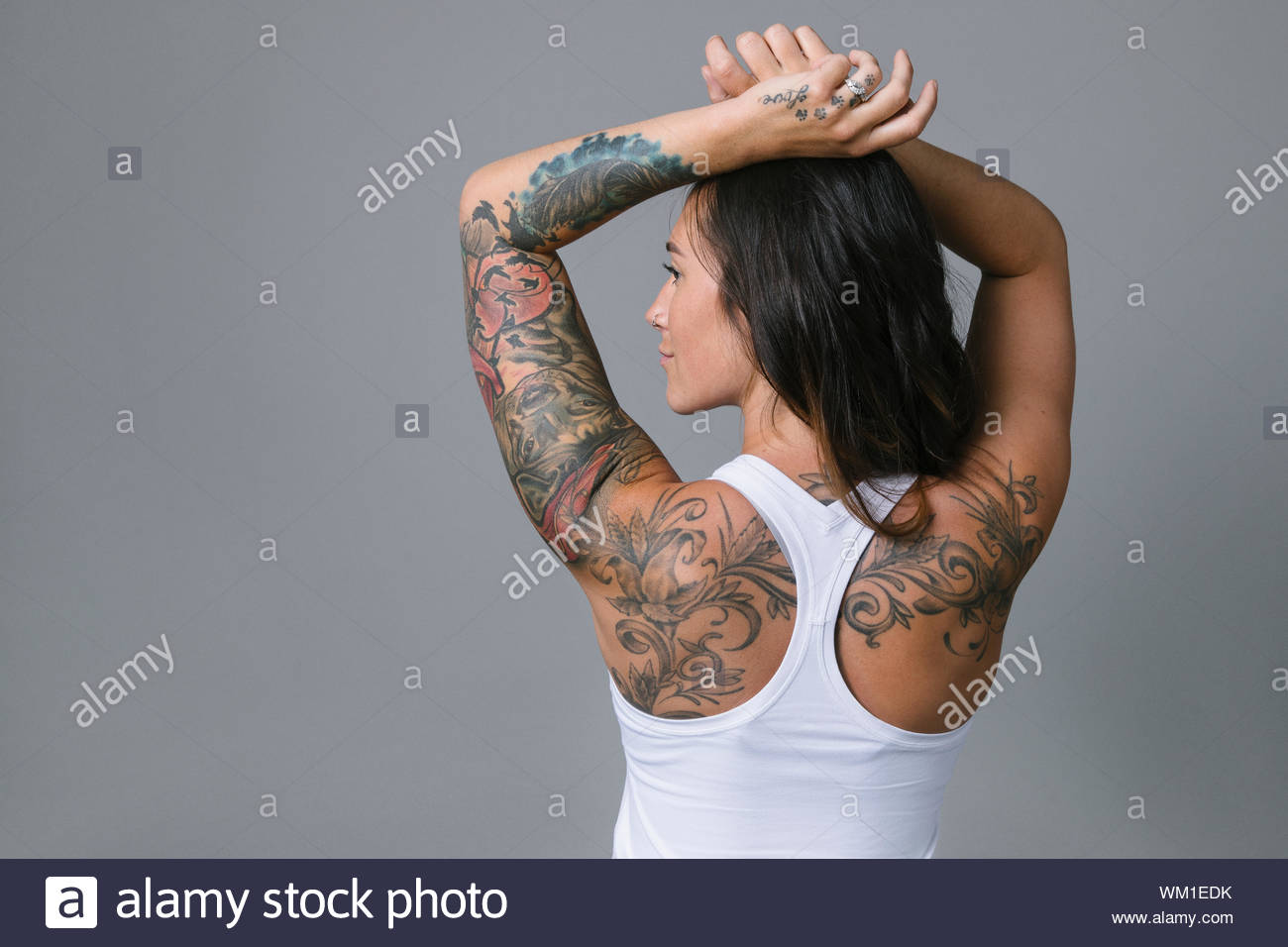 Rear view portrait young woman with tattoos wearing racerback tank top Stock Photo