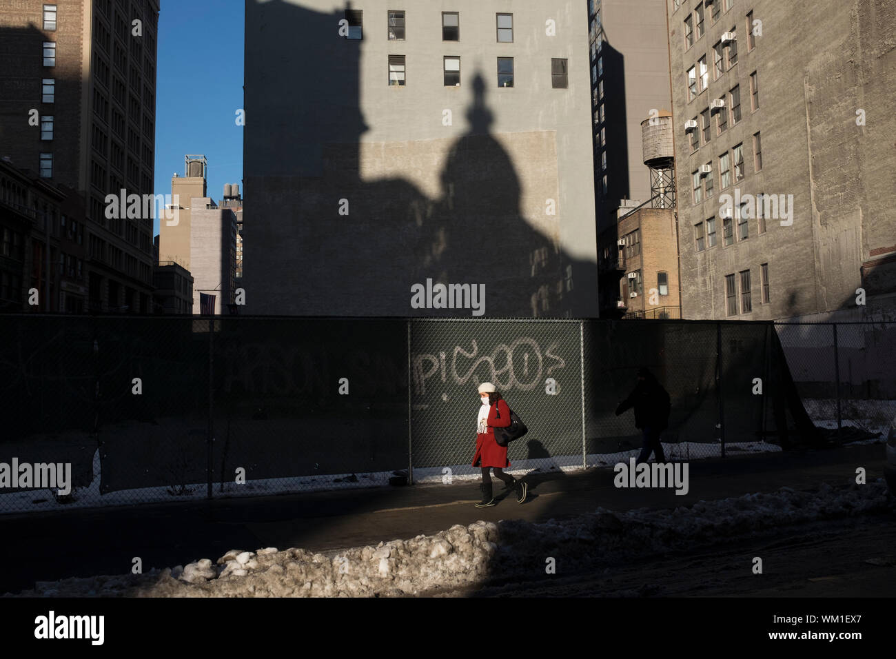 A woman walks down Broadway near 28th Street on a chilly weekday morning. The shadow of the Nomad Hotel is seen in the background. Stock Photo