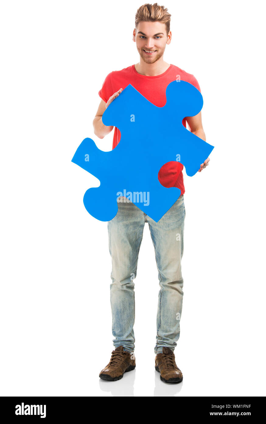 Good looking young man holding a blue puzzle piece, isolated on a white ...