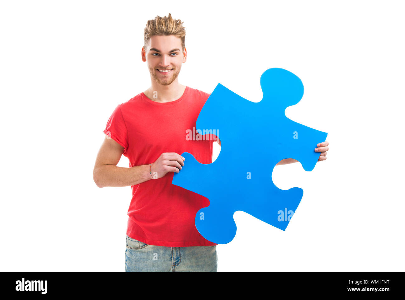 Good looking young man holding a blue puzzle piece, isolated on a white ...