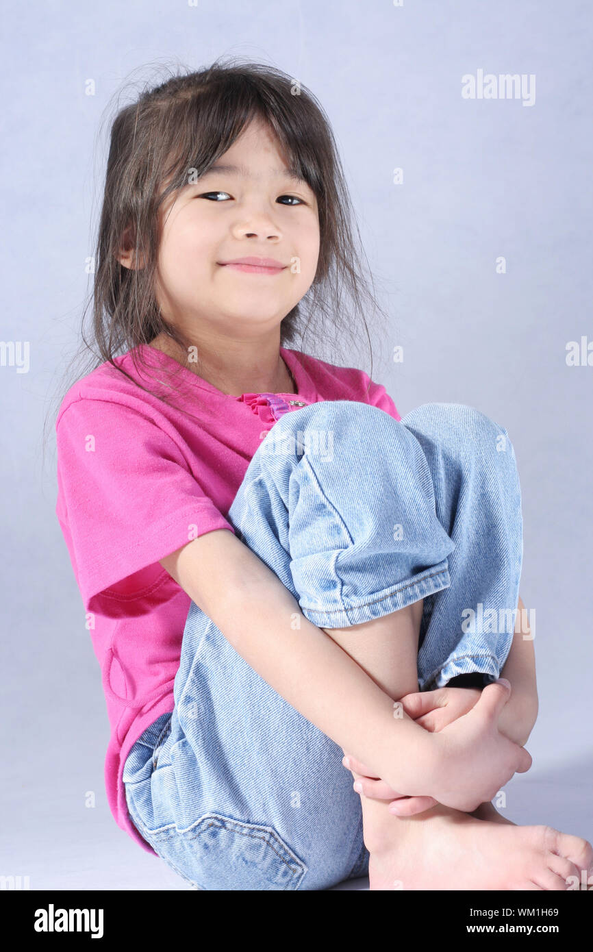 Little girl relaxing with arms around knees Stock Photo Alamy