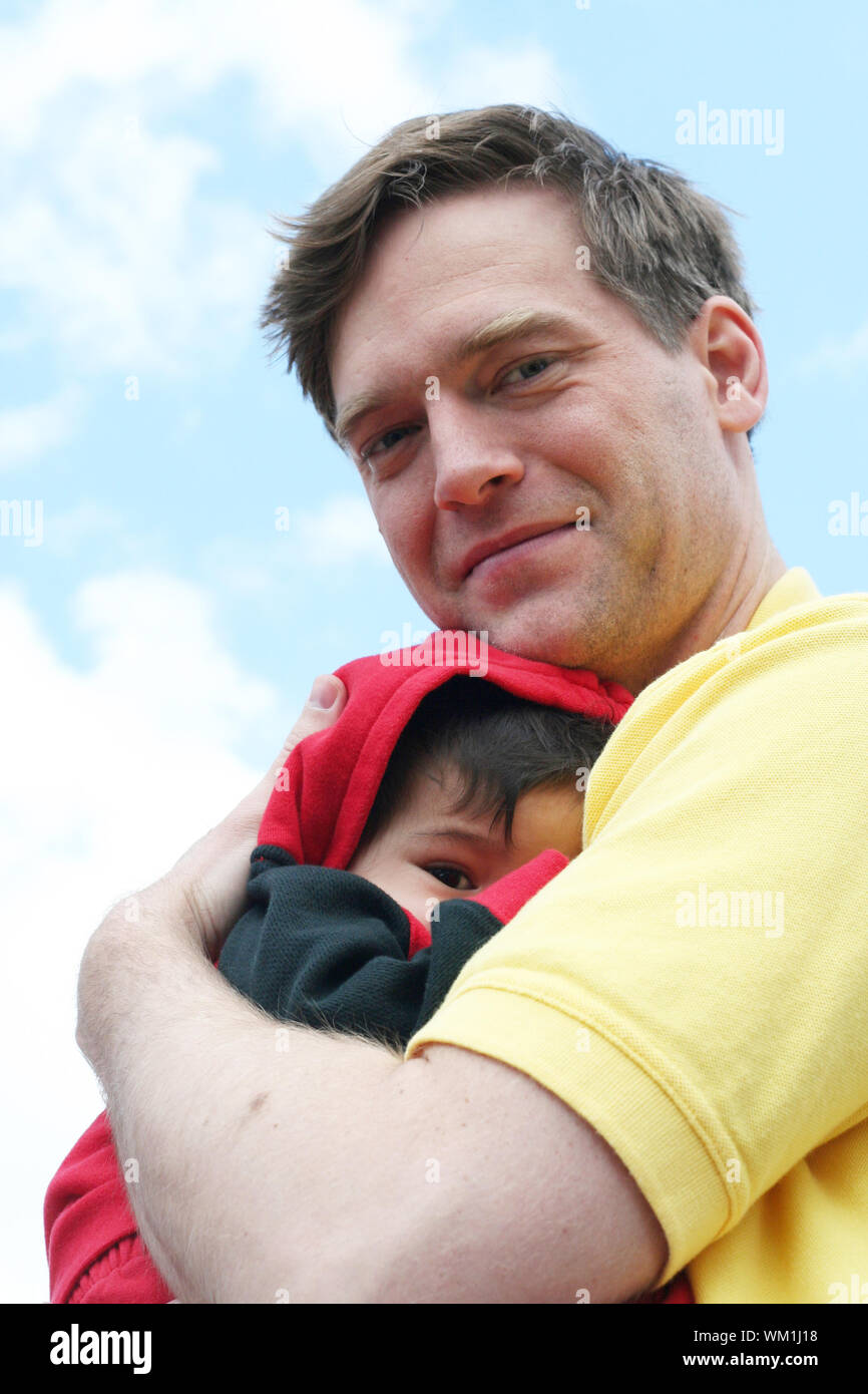 Baby cuddled safely in dad's arms Stock Photo