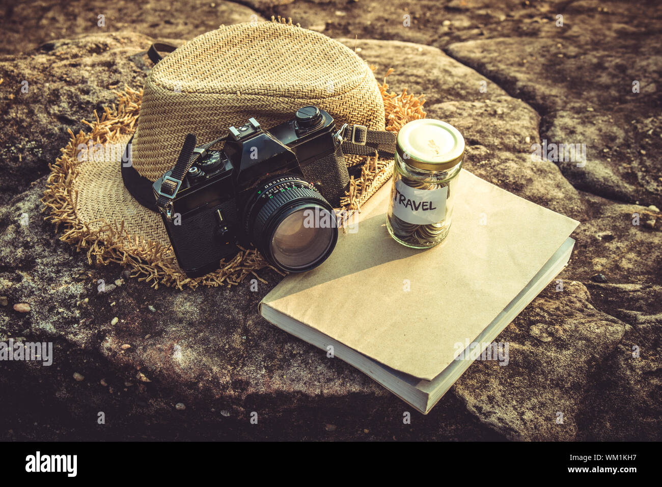 High Angle View Of Dslr Camera By Straw Hat And Coins In Jar On Book Stock Photo