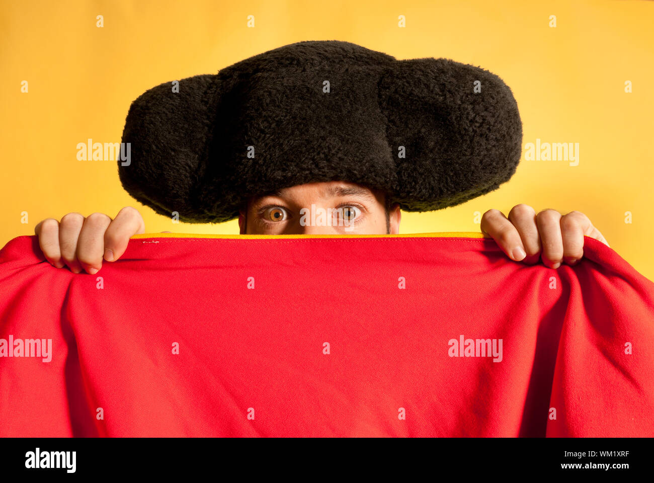 Bullfighter afraid with big montera hidden behind cape humor spanish colors Stock Photo