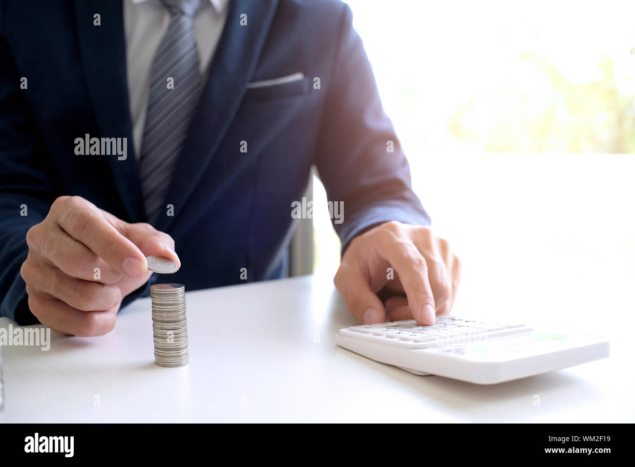 Midsection Of Businessman Calculating Coins Stock Photo